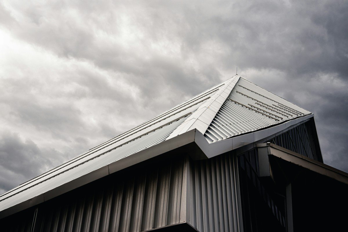 A metal roof ridge against a stormy gray sky