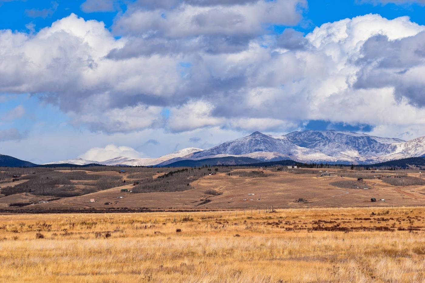 Open prairie with snow-dusted mountains under big clouds