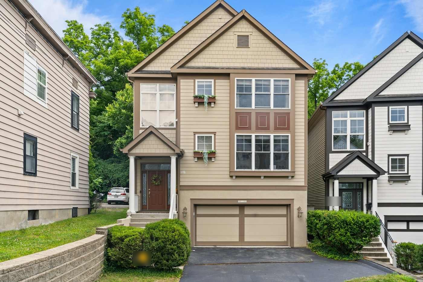 A tan two-story home with a two-car garage and gabled roof