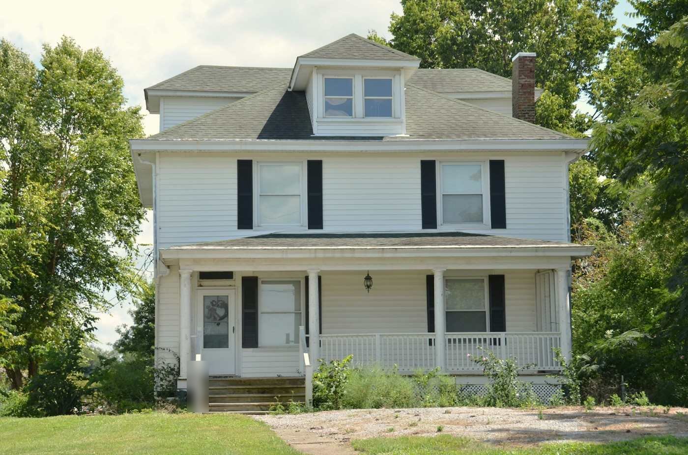 A white two-story house with a front dormer and a covered porch